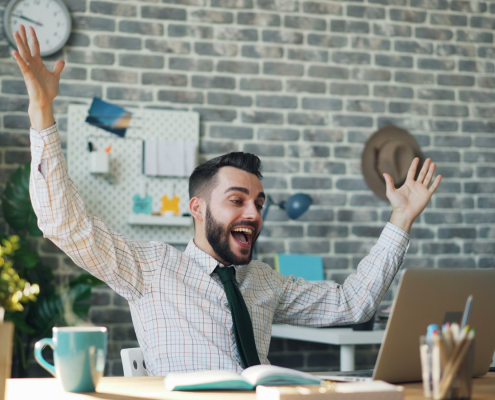 a man sitting at a desk with his arms in the air